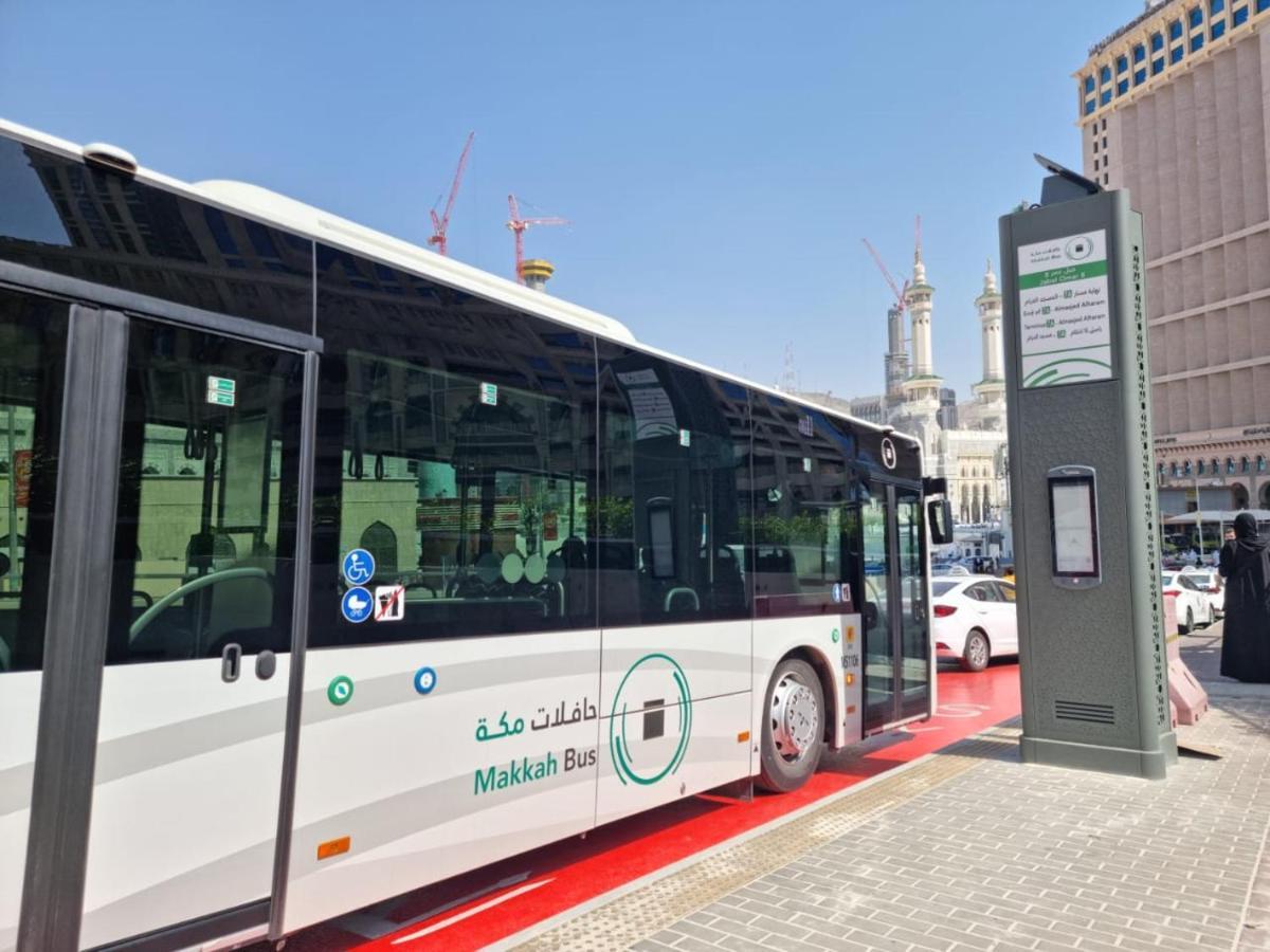 Hotel Jabal Omar Hyatt Regency Makkah Mekka Zewnętrze zdjęcie The photo shows a public bus labeled "Makkah Bus," parked at a designated bus stop. The bus has a modern design and is predominantly white, with green accents. In the background, there are tall buildings and construction cranes, indicating a busy urb