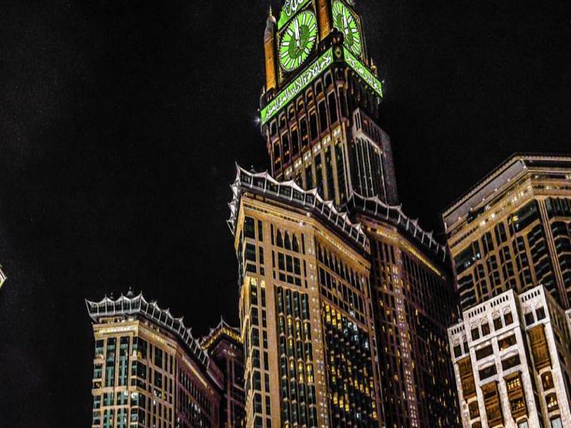 Hotel Jabal Omar Hyatt Regency Makkah Mekka Zewnętrze zdjęcie The photo shows a tall building, which is a prominent feature of a city skyline, illuminated against a dark night sky. At the top of the building is a large clock tower, noticeable for its distinct green color, and intricate architectural details. Th