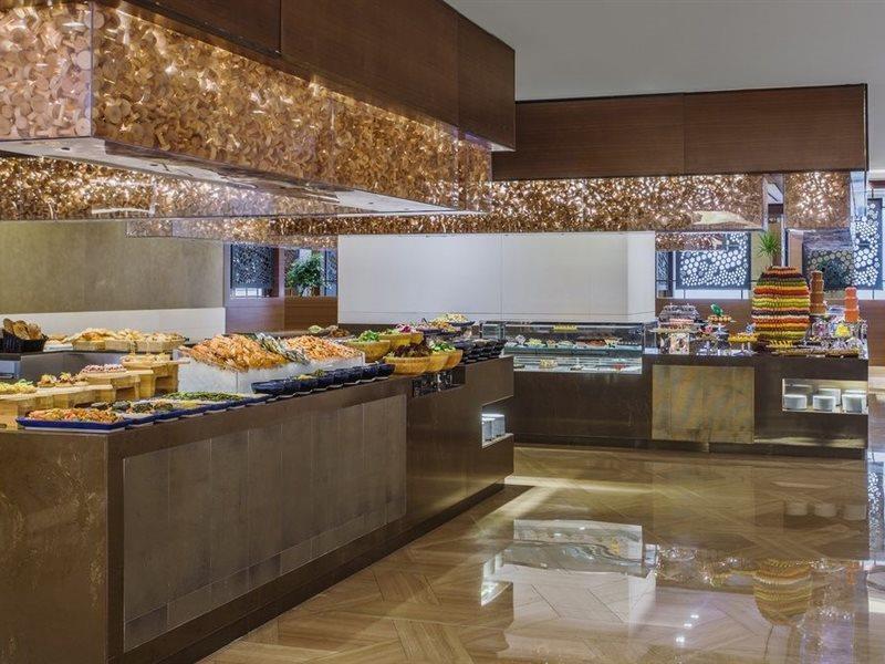 Hotel Jabal Omar Hyatt Regency Makkah Mekka Zewnętrze zdjęcie The photo shows a stylish buffet area, likely in a restaurant or hotel. There are several food displays arranged on long tables with shiny surfaces. The buffet features a variety of items, which may include pastries, bread, and other dishes. The area