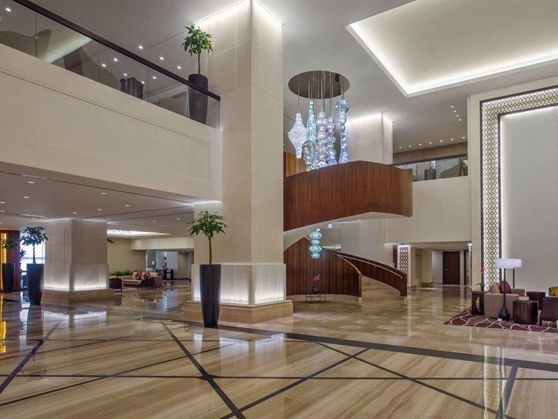 Hotel Jabal Omar Hyatt Regency Makkah Mekka Zewnętrze zdjęcie The image shows a spacious and modern hotel lobby. It features elegant interior design with high ceilings and polished marble floors. A prominent wooden staircase with a stylish design is located in the center, leading to an upper level. There are de