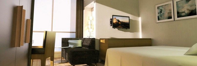 Hotel Jabal Omar Hyatt Regency Makkah Mekka Zewnętrze zdjęcie The photo shows a modern hotel room or living space featuring a small seating area. On the left, there is a dark-colored couch and a glass side table. Across from the couch, mounted on the wall, is a flat-screen television. The room has light-colored