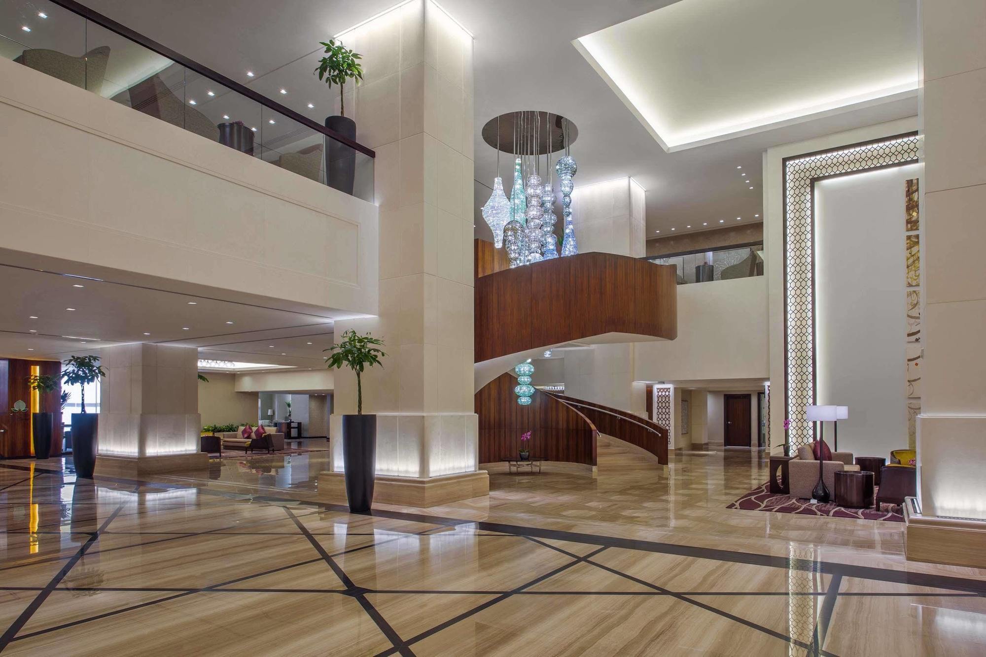 Hotel Jabal Omar Hyatt Regency Makkah Mekka Zewnętrze zdjęcie The photo shows a spacious and elegantly designed hotel lobby. The interior features large marble flooring with a geometric pattern, complemented by modern lighting fixtures. A grand staircase with wooden accents is prominent in the center, leading t