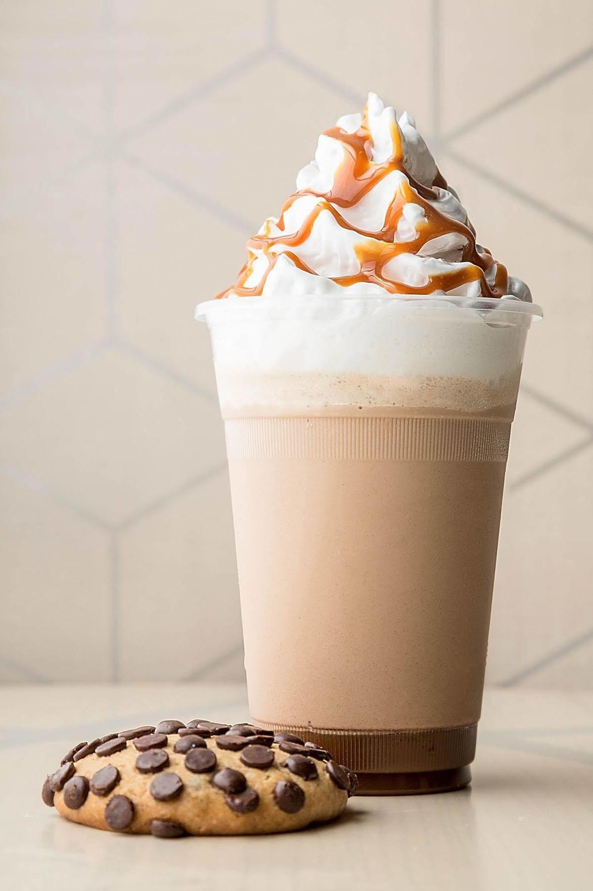 Hotel Jabal Omar Hyatt Regency Makkah Mekka Zewnętrze zdjęcie The photo shows a tall cup of a creamy beverage, likely a milkshake or a blended coffee drink. The drink has a light brown color with a frothy top, which is topped with whipped cream. Drizzled over the whipped cream is a thick caramel sauce, adding a