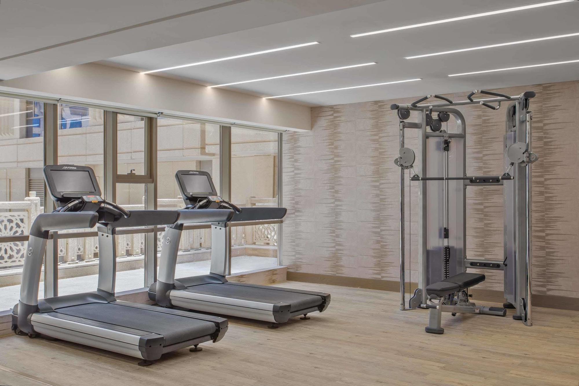 Hotel Jabal Omar Hyatt Regency Makkah Mekka Zewnętrze zdjęcie The photo shows a modern gym area featuring two treadmills positioned side by side. Next to them is a multi-functional gym machine designed for strength training, which includes various attachments for different exercises. The gym has a bright, airy 