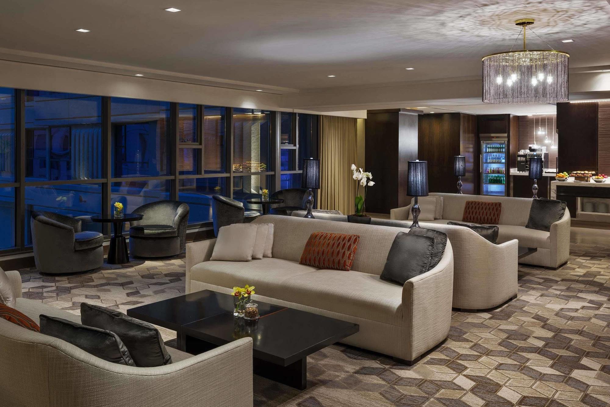 Hotel Jabal Omar Hyatt Regency Makkah Mekka Zewnętrze zdjęcie The photo shows a modern and elegant lounge area. It features comfortable cream-colored sofas arranged in a cozy setting, along with dark coffee tables. The space is illuminated by warm lighting, including a stylish chandelier. Large windows allow fo